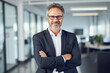 © Rytis - Business concept. Portrait of middle aged business man ceo standing in office with arms crossed. Neutral office background with copy space. Generative AI