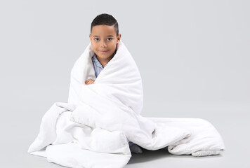 Poster - Little African-American boy with soft blanket sitting on light background