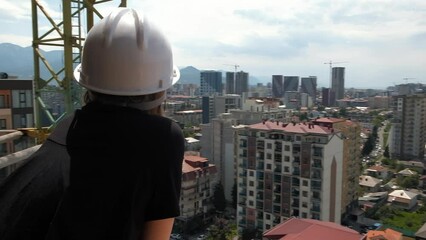 Wall Mural - Back close up of young woman worker in hard hat at a construction site