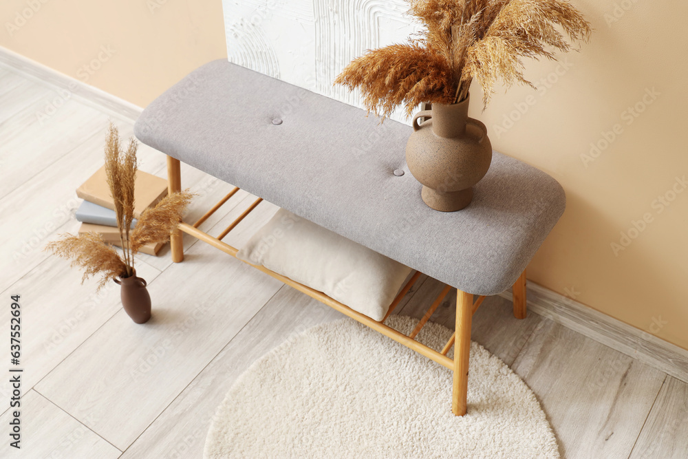 Interior of stylish room with soft bench near beige wall