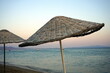 Große runde Sonnenschirme aus Korbgeflecht vor blauem Himmel im Licht der Abendsonne im Sommer am Strand von Sarimsakli bei Ayvalik in der Provinz Balikesir in der Türkei