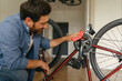 © Daria - Smiling man in casual clothing cleans the bike from dirt after repair at home kitchen