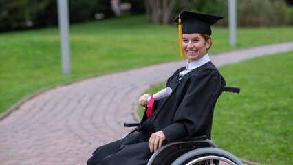 Happy caucasian woman in a wheelchair holding her diploma outdoors.