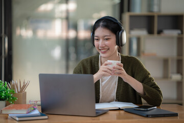 Asian women wearing headphones study online watch webinar podcasts on laptops listen to learning education course conference calling, and e-learning concepts.