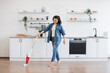 © sofiko14 - Asian lady using upright vacuum with music in headphones