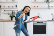 © sofiko14 - Female with upright vacuum singing along track in headphones