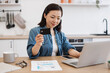 © sofiko14 - Female in headset holding credit card behind laptop at home