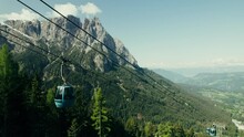 Drone View Of The Cable Car Among The Rocky Mountains, The Slopes Of Which Are Covered With Spruce Forest. Aerial Video Shooting On A Summer Day