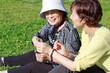 シニア女性と芝生の上でクローバーを渡す。親子と感謝のイメージ
