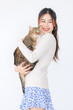 © Bangkok Click Studio - Isolated cutout studio shot Asian young pretty sexy female teenager girl model in turtleneck sweater standing holding cute little domestic tabby short hair companion pet cat kitty on white background
