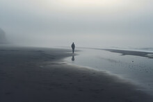 A Lone Individual On A Misty Beach Symbolizes Feelings Of Isolation And Introspection Often Associated With Depression