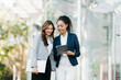 © Nuttapong punna - Business woman team going in city center in smart casual business style, talking, working together, stylish freelance people, holding coffee and laptop,tablet and smartphone discussing.