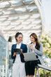 © Nuttapong punna - Business woman team going in city center in smart casual business style, talking, working together, stylish freelance people, holding coffee and laptop,tablet and smartphone discussing.