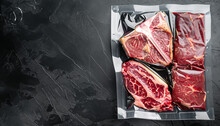 Dry Aged Steak In A Vacuum. Meat Products In Plastic Pack Set, Tomahawk, T Bone And Club Steak Cuts, On Black Stone Background, Top View Flat Lay, With Copy Space For Text