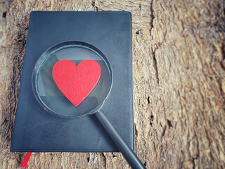 A bible with a magnifying glass and red heart in vintage background. Christian faith hope love concept.