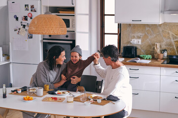 Happy family embracing candid daughter at kitchen table