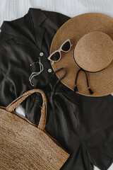 Wall Mural - Aesthetic fashion composition with female clothes and accessories. Black linen shirt and shorts, sunglasses, straw hat, rattan handbag. Flat lay, top view