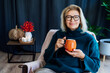 © okrasiuk - Middle aged woman relaxing with pumpkin shaped cup of hot drink in scandy style hygge interior home with fall mood decor. Lady dreaming, enjoy calm mood without stress, well being alone. Cozy autumn
