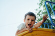 © alexkoral - happy preschooler boy playing on slide on playground in summer
