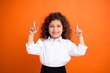 Wall Mural - Portrait of charming cheerful schoolchild toothy smile indicate fingers up empty space ad isolated on orange color background