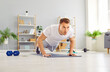 Portrait of a young attractive sporty man doing push-up or plank sport exercises lying on yoga mat on the floor in the living room at home. Fitness, workout and home training concept.