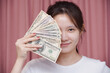 Portrait of asian woman wear white shirt a smiling and counting holding in hand banknotes or money us dollar exchange money USD on pink background. Business finance and bank employee Concept.