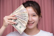 Portrait of asian woman wear white shirt a smiling and counting holding in hand banknotes or money us dollar exchange money USD on pink background. Business finance and bank employee Concept.