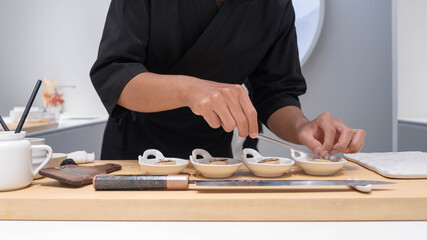 Wall Mural - Professional chef preparing and cooking raw fresh fish ingredient on the table with knife for delicious sushi and sashimi meal, Person making luxury omakase fine dining Japanese food restaurant dinner