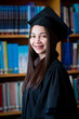 © EduLife Photos - Portrait young happy and excited Asian woman university graduate in graduation gown and cap in the library. Education stock photo