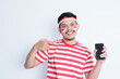 A portrait of a smiling Asian man wearing headband and showing his phone, isolated by white background. Indonesia's independence day concept