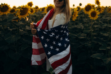 Young woman holding American flag at sunset. America celebrate 4th of July. Independence Day.