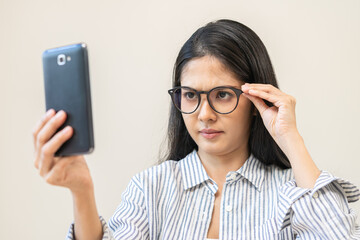 Wall Mural - Presbyopia, Hyperopia middle aged asian woman holding eyeglasses problem with vision blurred ,trying to read text message from smart mobile phone screen, eye disease of old, eyesight farsightedness.