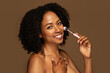 © Prostock-studio - Cheerful pretty half-naked young black woman holding makeup brush