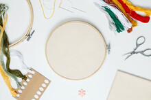 Embroidery Set Fot Stitching. Beige Cotton Cloth In Embroidery Hoop On White Background With Fabric, Colorful Threads, Scissors And Needls. Indoor Hobby Concept With Copy Space, Top View