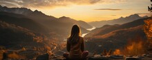 Sunrise panorama of a young woman doing yoga in the mountains.
