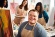 © Jasmina - Young smiling man with Down syndrome on art workshop with a group of students, learning a new skill. Social integration concept.