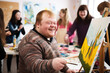 © Jasmina - Young smiling man with Down syndrome on art workshop with a group of students, learning a new skill. Social integration concept.