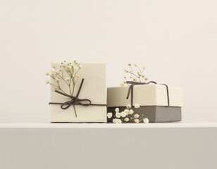 Craft gift boxes with flower on light beige background. Copy space for text message. Minimalism style template background.