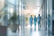 © olegganko - Three people walking down hallway in hospital
