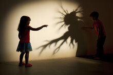 Kids Playing With Shadows On A Wall Using A Flashlight. 