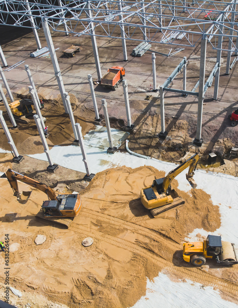 Construction site of a large warehouse storage building and logistics center, heavy vehicle working, excavator, crane, truck and bulldozer, steel frame structure of modern factory hangar, aerial view