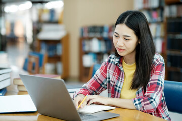 Poster - Young university student using laptop for online learning, searching and learning at library.