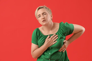 Poster - Mature woman having heart attack on red background