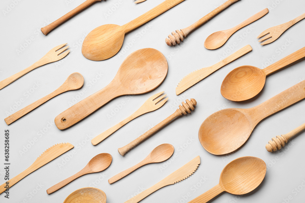 Wooden spoons with forks and knives on grey background