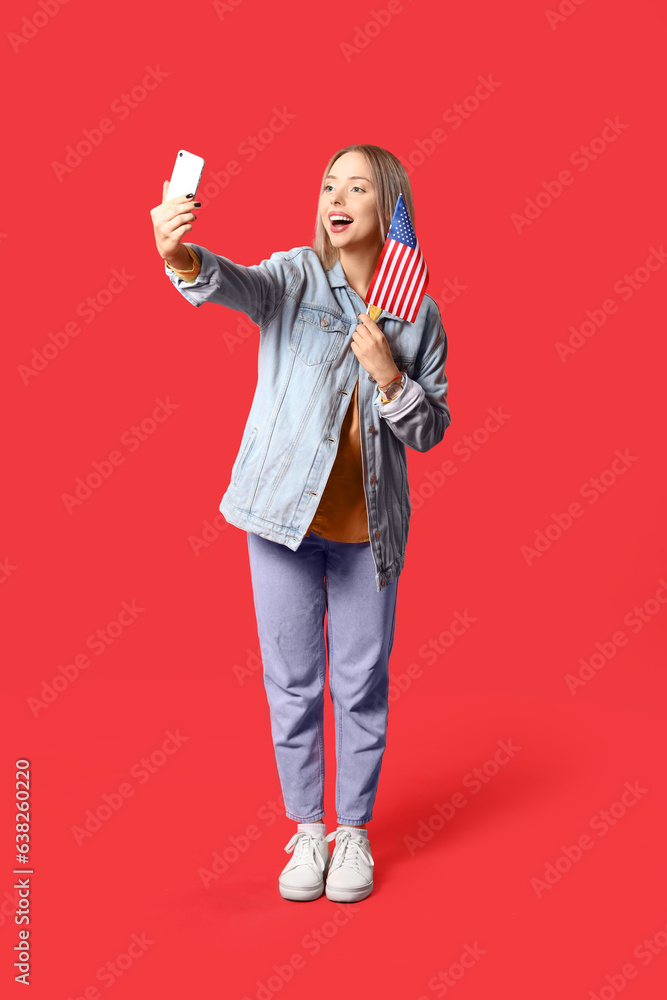 Young woman with USA flag taking selfie on red background