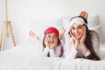 Wall Mural - Happy mother and her little daughter with sleeping masks in bedroom