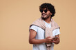 © New Africa - Handsome young smiling man in sunglasses on beige background. Space for text