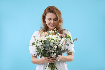 Wall Mural - Beautiful woman with bouquet of flowers on light blue background