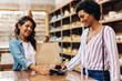 © (JLco) Julia Amaral - Cheerful female customer making an NFC payment in a ceramic store