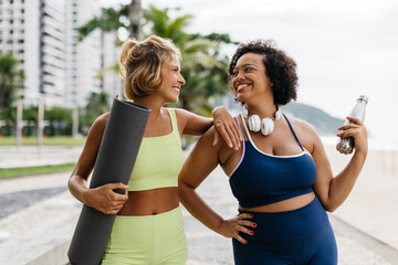 Wall Mural - Two friends enjoying a beach workout with yoga mat and water bottle